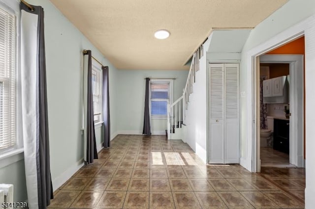 hallway featuring stairway, tile patterned flooring, and baseboards