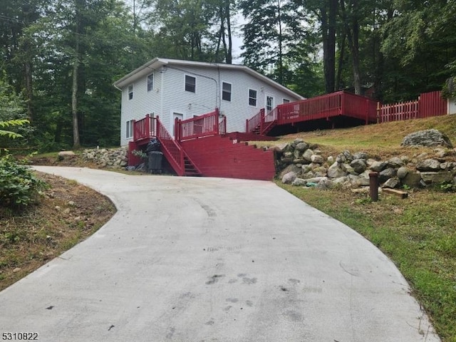 view of front of home with stairs, driveway, and a wooden deck