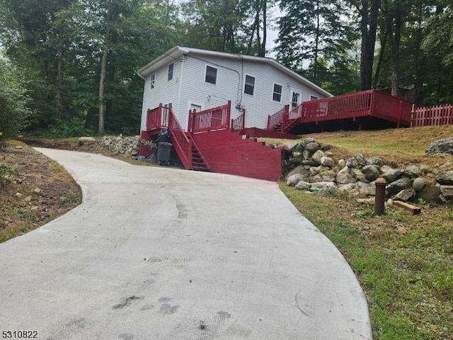 view of front of home featuring concrete driveway, stairway, and a wooden deck