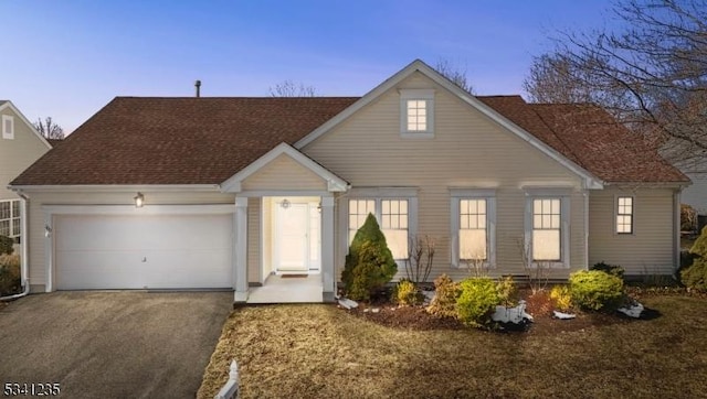 view of front of property featuring a garage, driveway, and a shingled roof