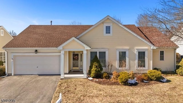 view of front of home with a garage, driveway, and roof with shingles