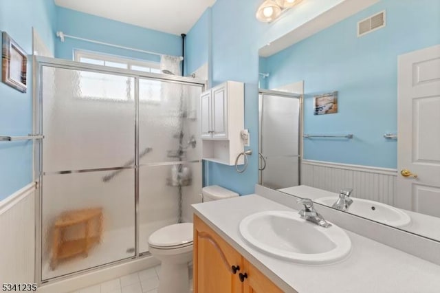 bathroom featuring visible vents, a wainscoted wall, a shower stall, and toilet