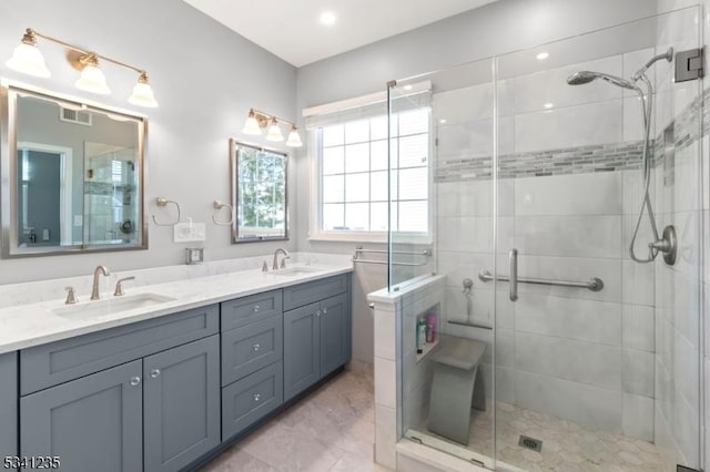 bathroom featuring double vanity, a stall shower, visible vents, and a sink