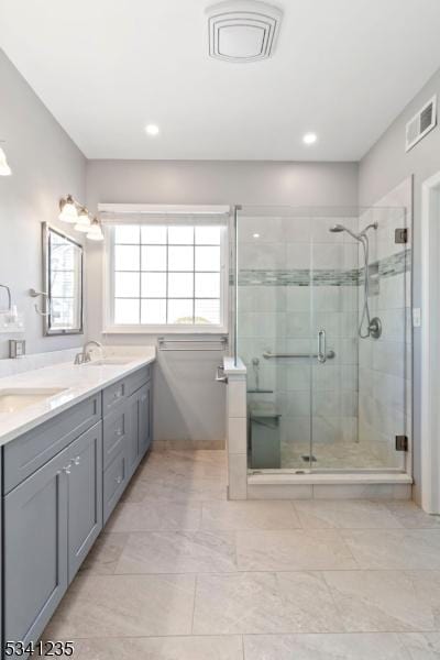 bathroom featuring double vanity, a stall shower, a sink, and visible vents