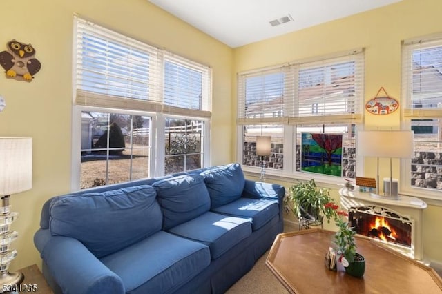 living room with a warm lit fireplace and visible vents