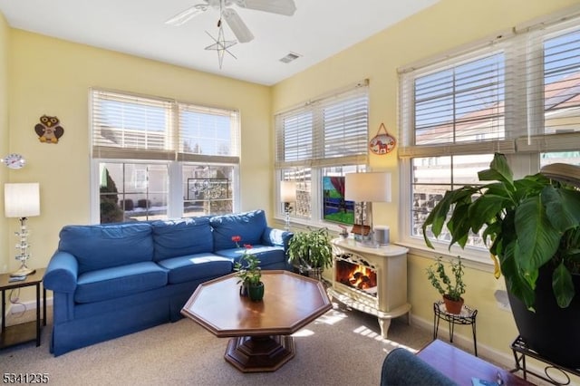 carpeted living room with visible vents, a ceiling fan, and baseboards