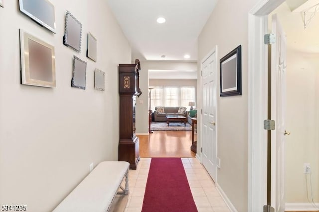 corridor featuring baseboards, light tile patterned floors, and recessed lighting