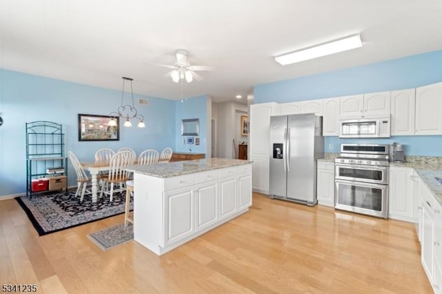 kitchen with light wood-style flooring, pendant lighting, stainless steel appliances, and a center island