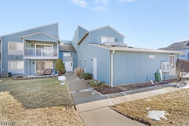 multi unit property with cooling unit, a balcony, and a front yard