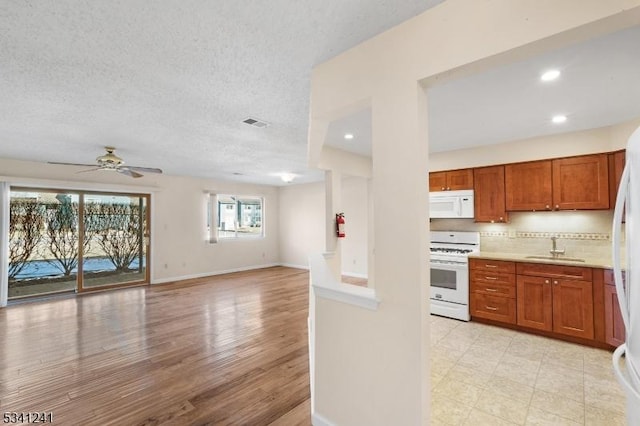 kitchen with brown cabinets, light countertops, backsplash, white appliances, and baseboards