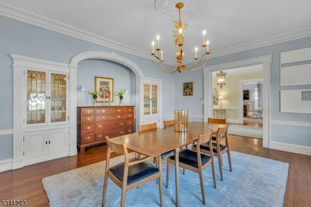 dining room featuring baseboards, crown molding, an inviting chandelier, and wood finished floors