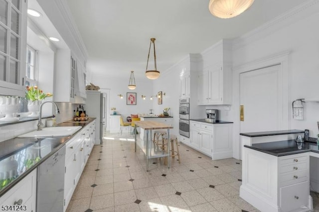 kitchen with dishwasher, crown molding, a kitchen island, and a sink