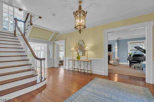 entryway with stairs, wood finished floors, and ornamental molding