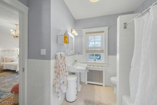 ensuite bathroom featuring tile patterned floors, a wainscoted wall, toilet, ensuite bath, and radiator