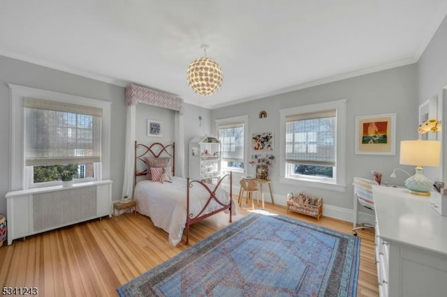 bedroom with radiator, baseboards, a chandelier, light wood-type flooring, and ornamental molding