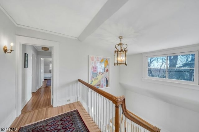 corridor featuring light wood-type flooring, baseboards, and a chandelier