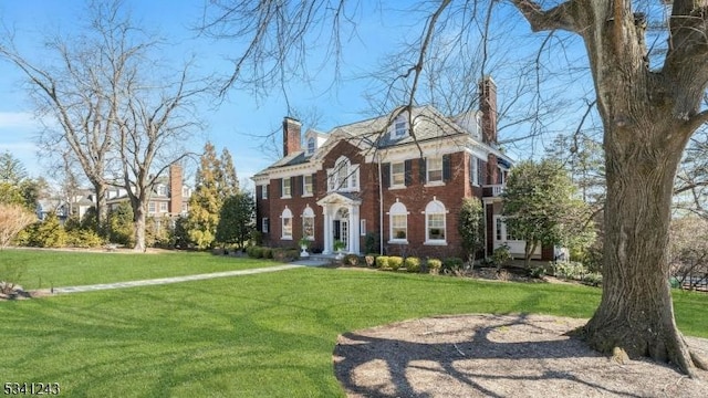 colonial home with a front yard, brick siding, and a chimney