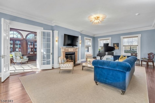 living room with a glass covered fireplace, wood finished floors, crown molding, and french doors