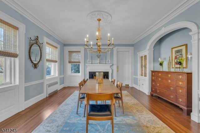 dining room with an inviting chandelier, wood finished floors, radiator heating unit, and ornamental molding