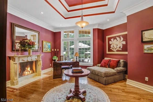 sitting room featuring a raised ceiling, a premium fireplace, ornamental molding, wood finished floors, and baseboards