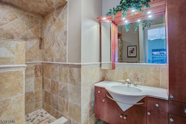 bathroom with a tile shower, tile walls, and vanity