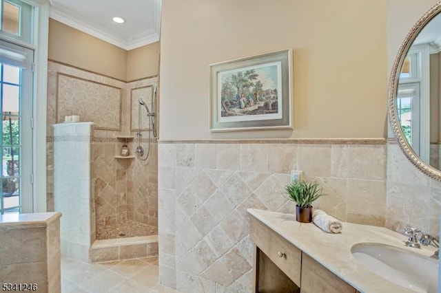 bathroom featuring wainscoting, walk in shower, crown molding, vanity, and tile walls