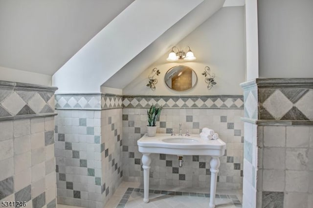 bathroom with vaulted ceiling and a wainscoted wall