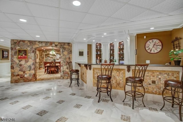 bar with arched walkways, a dry bar, and a drop ceiling