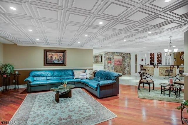 living area with an inviting chandelier, wood finished floors, an ornate ceiling, and recessed lighting