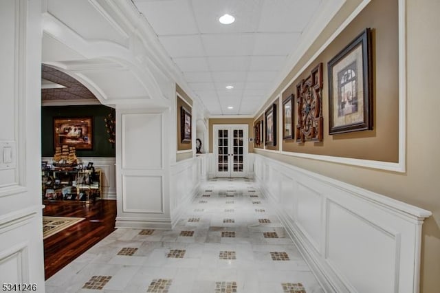 corridor with a wainscoted wall, french doors, recessed lighting, and a decorative wall