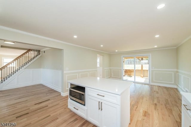 kitchen featuring white cabinetry, stainless steel microwave, and light wood-style floors