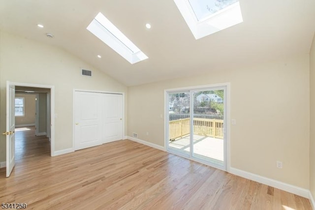 spare room featuring light wood-type flooring, a healthy amount of sunlight, a skylight, and visible vents