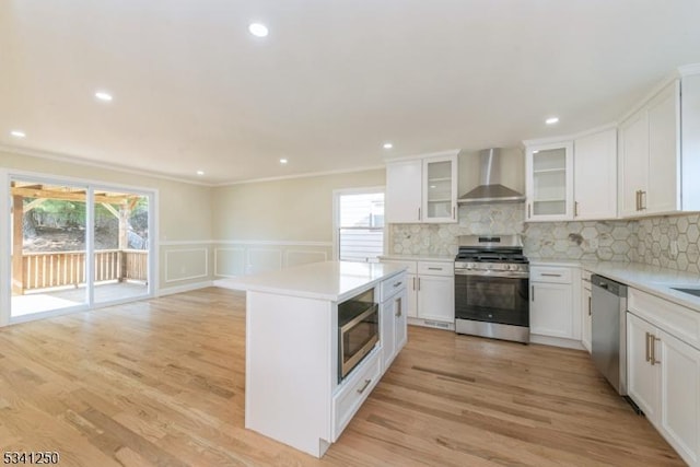 kitchen featuring light countertops, wall chimney range hood, light wood-style floors, and stainless steel appliances