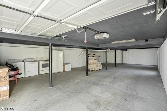 garage featuring a garage door opener, freestanding refrigerator, and washer and dryer