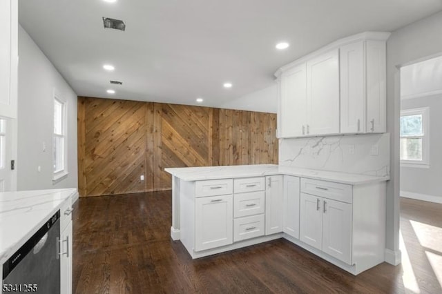 kitchen featuring dark wood-style flooring, stainless steel dishwasher, white cabinets, light stone countertops, and a peninsula