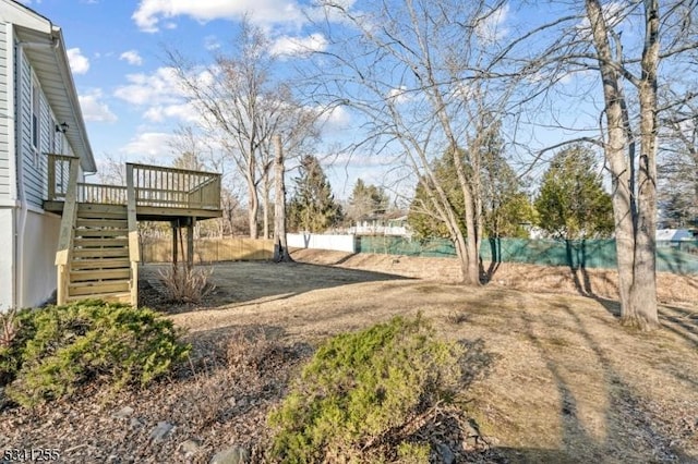 view of yard with fence, a wooden deck, and stairs