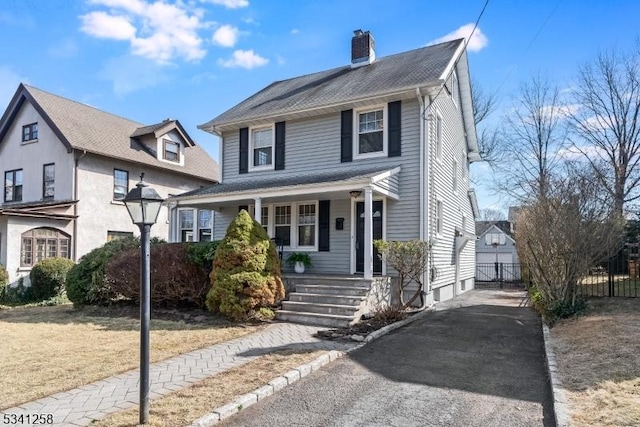 american foursquare style home with driveway, a porch, and a chimney