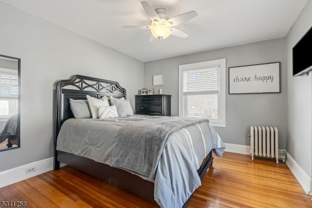 bedroom featuring baseboards, multiple windows, wood finished floors, and radiator