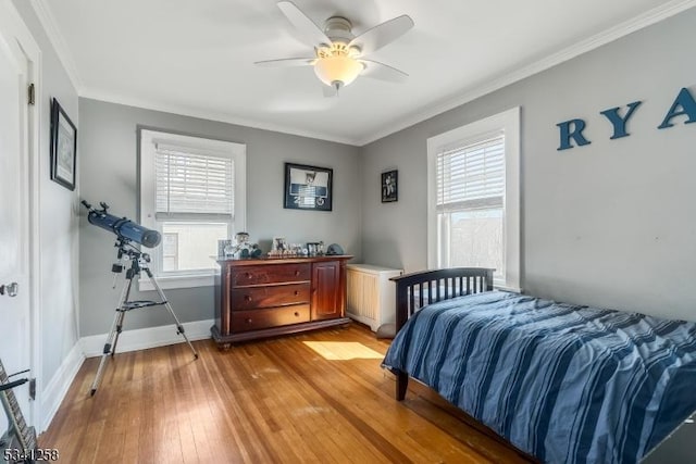 bedroom with baseboards, crown molding, light wood finished floors, and ceiling fan