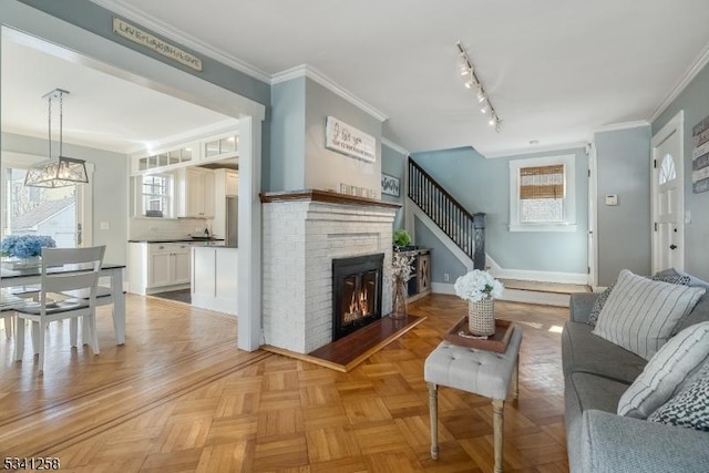 living area with baseboards, a fireplace, rail lighting, and crown molding