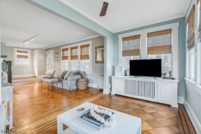 living room featuring baseboards, a ceiling fan, radiator heating unit, rail lighting, and crown molding