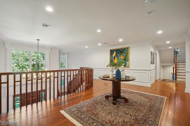 hallway with recessed lighting, visible vents, ornamental molding, wainscoting, and wood finished floors