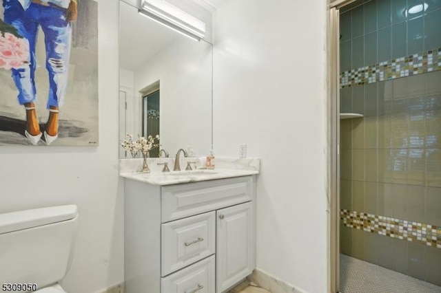 full bathroom featuring tiled shower, vanity, and toilet