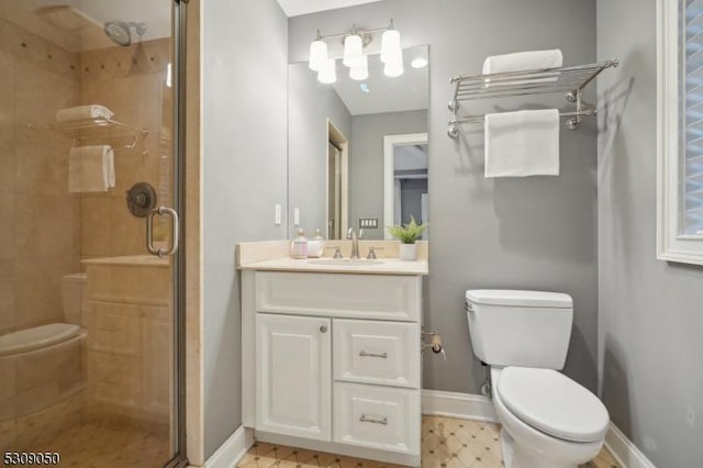 bathroom featuring toilet, a stall shower, vanity, baseboards, and tile patterned floors