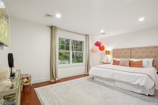 bedroom with baseboards, wood finished floors, visible vents, and recessed lighting