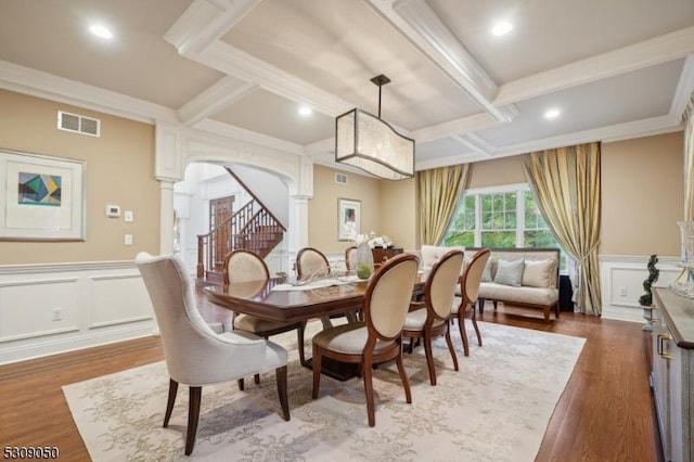 dining room with arched walkways, a decorative wall, coffered ceiling, visible vents, and decorative columns