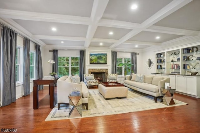 living area with beamed ceiling, wood finished floors, and a healthy amount of sunlight