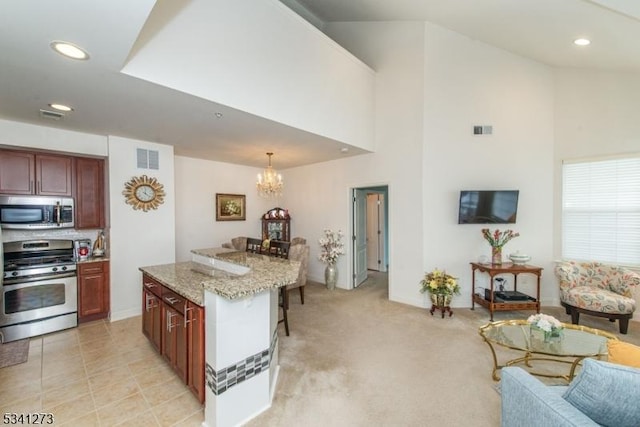 kitchen featuring visible vents, a chandelier, appliances with stainless steel finishes, light stone countertops, and high vaulted ceiling