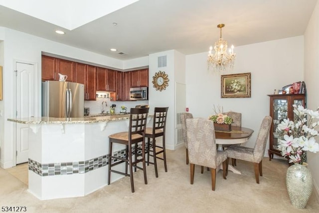 kitchen featuring light stone counters, a breakfast bar area, visible vents, appliances with stainless steel finishes, and a sink