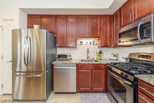 kitchen featuring stainless steel appliances, a sink, dark brown cabinets, and light stone countertops